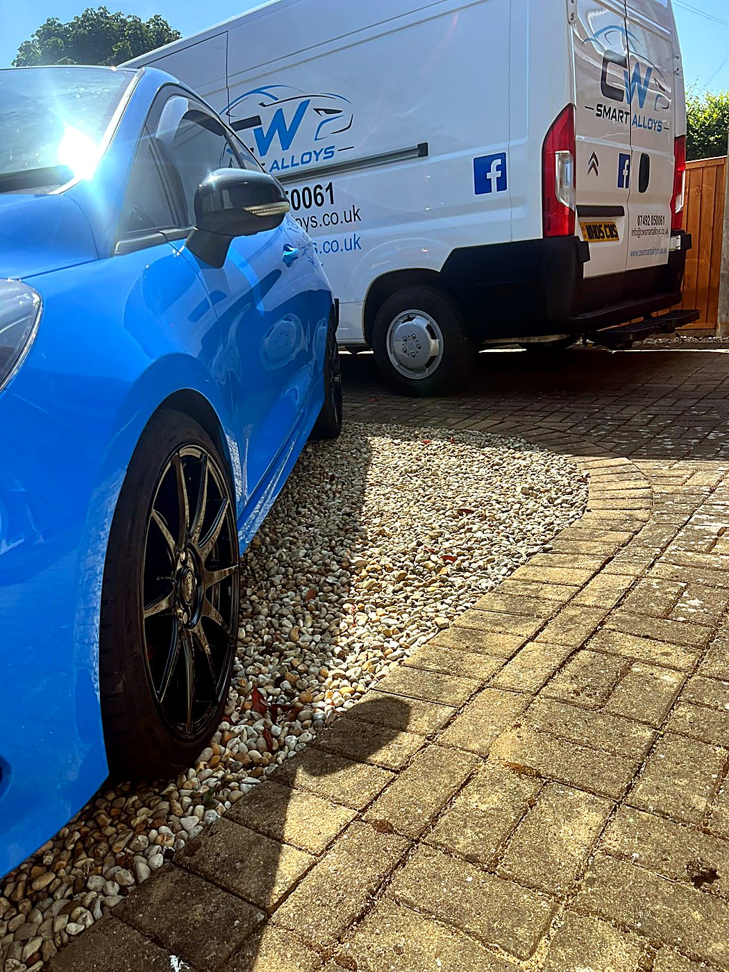 Blue Ford Focus RS with fresh gloss black alloys parked beside the CW Smart Alloys van